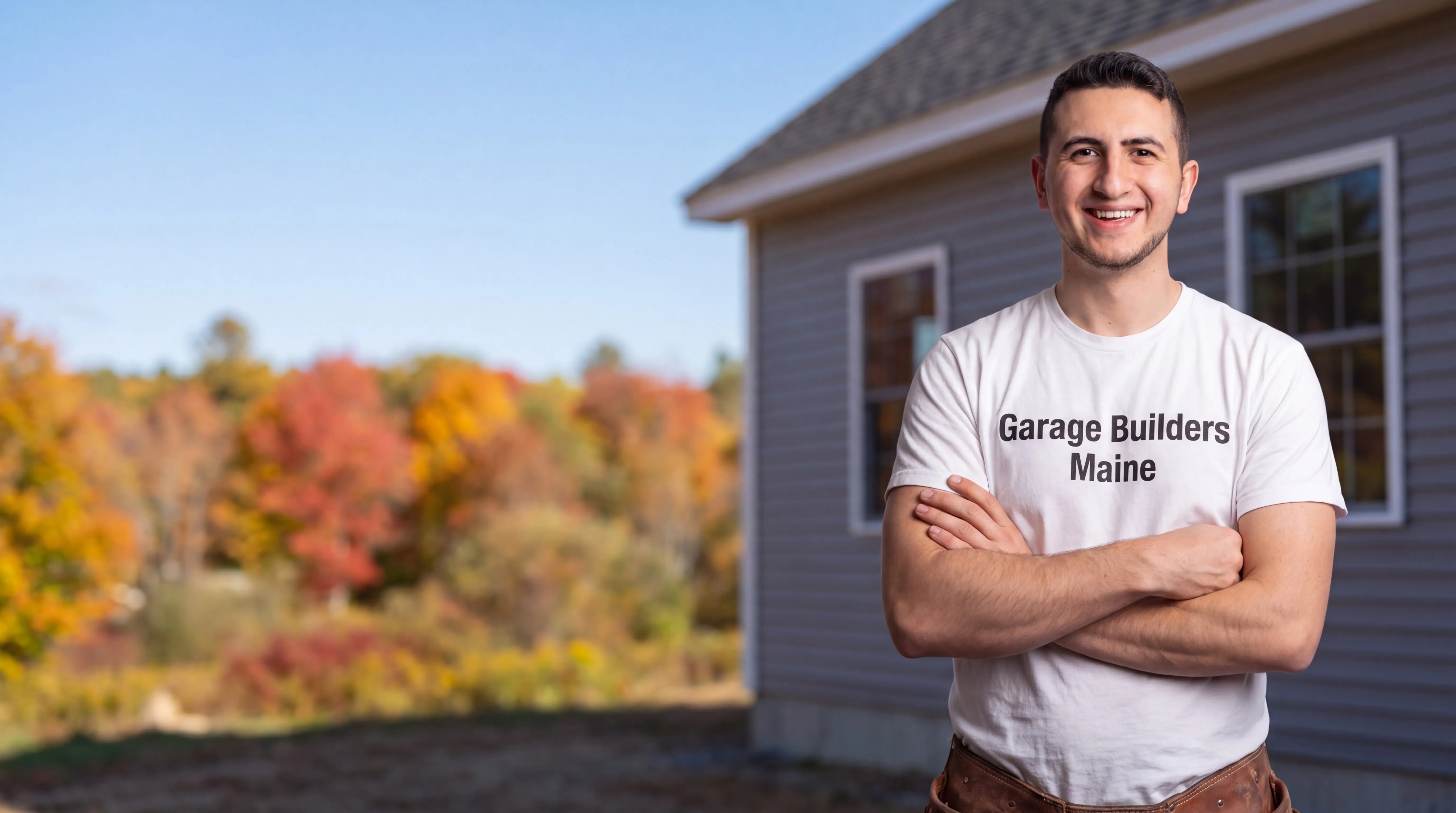 Owner of Garage Builders Maine standing with his arms crossed and smiling at a Maine job site