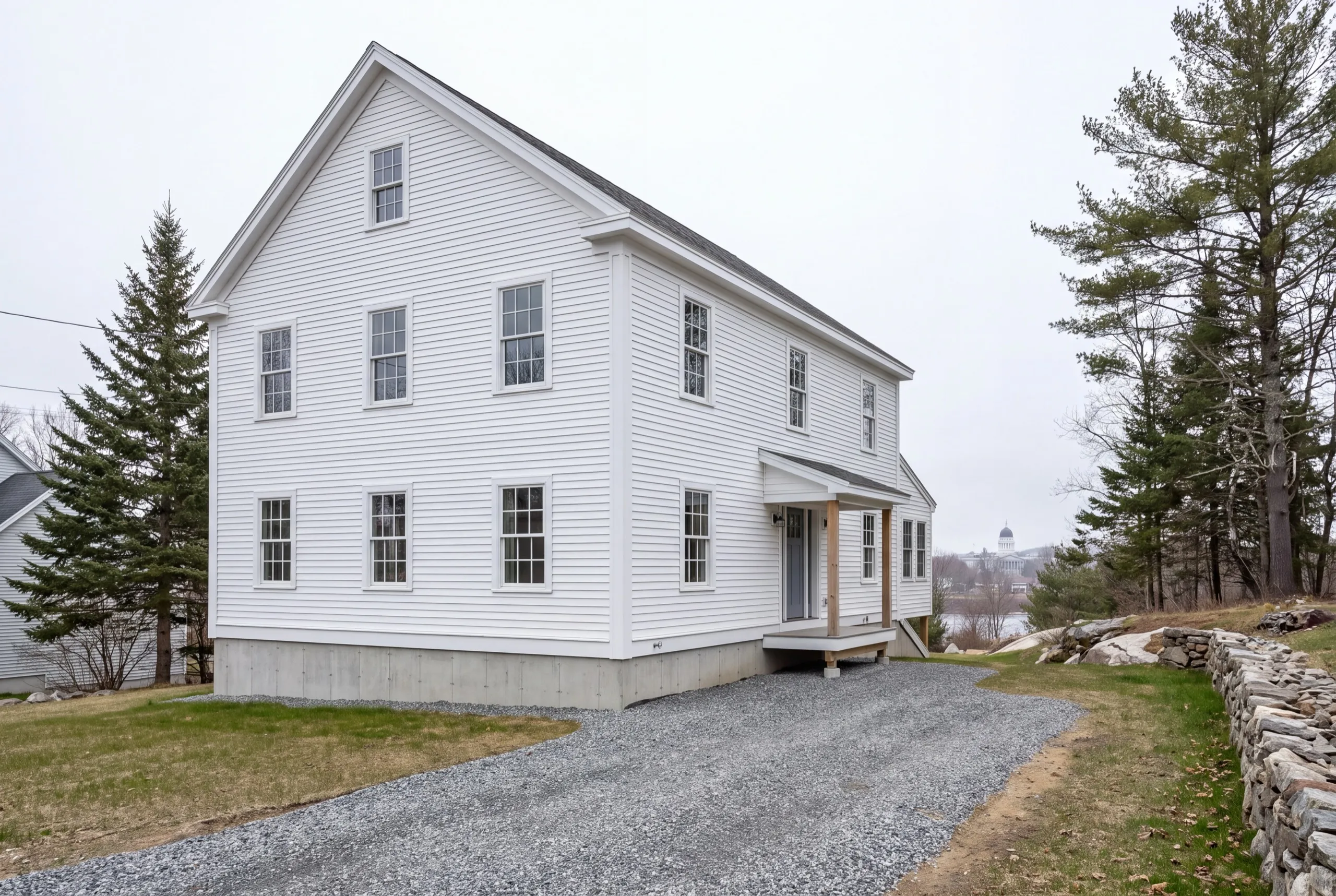 Residential home builder Augusta Maine: finished white two-story house with its gable end to the drive