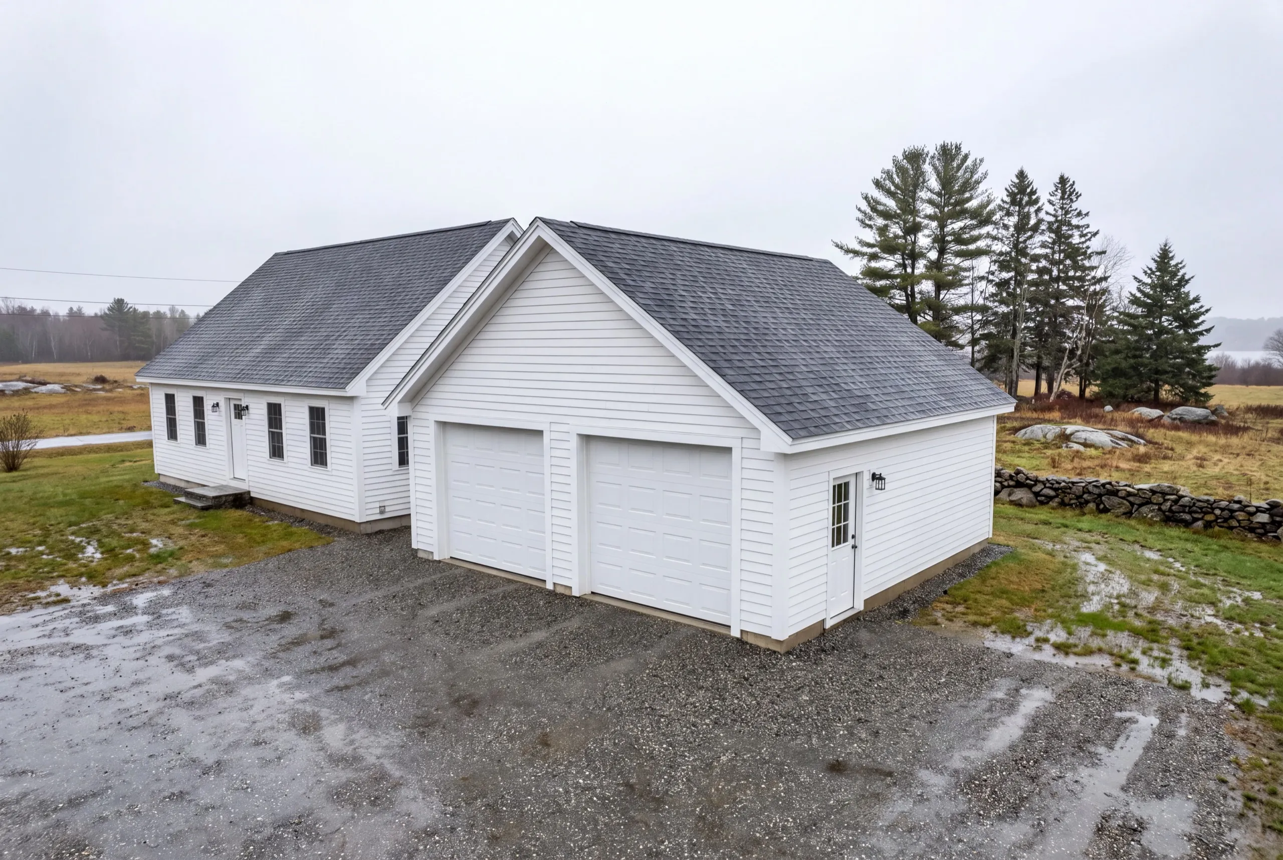 Garage builders Sidney Maine: white two-bay garage attached to the gable end of a white cape