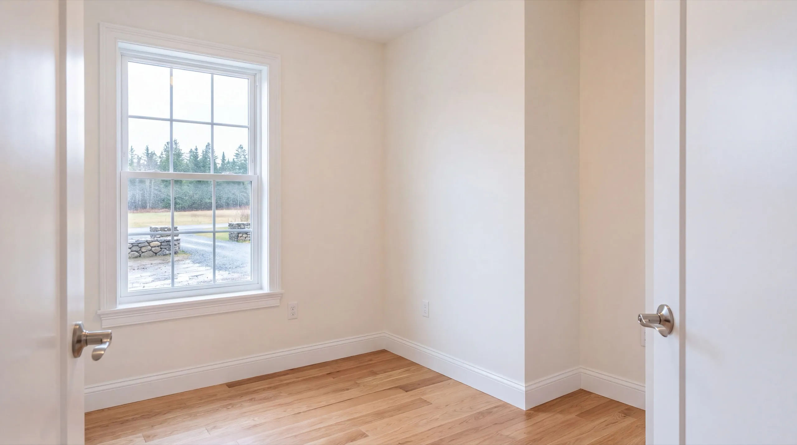 Residential general contractor Chelsea Maine: finished bedroom with a white double-hung window and wood floor