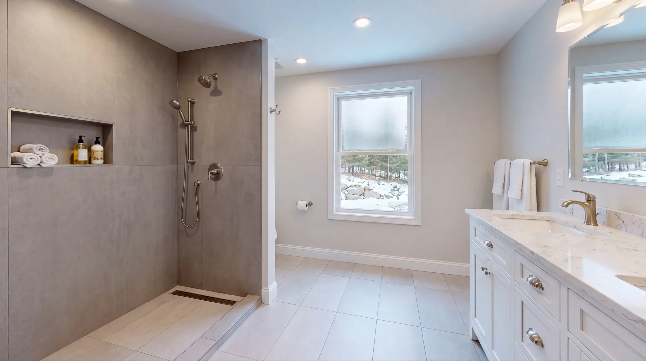 Remodeling Farmingdale Maine: open walk-in shower with gray tile, a linear drain and a white double vanity