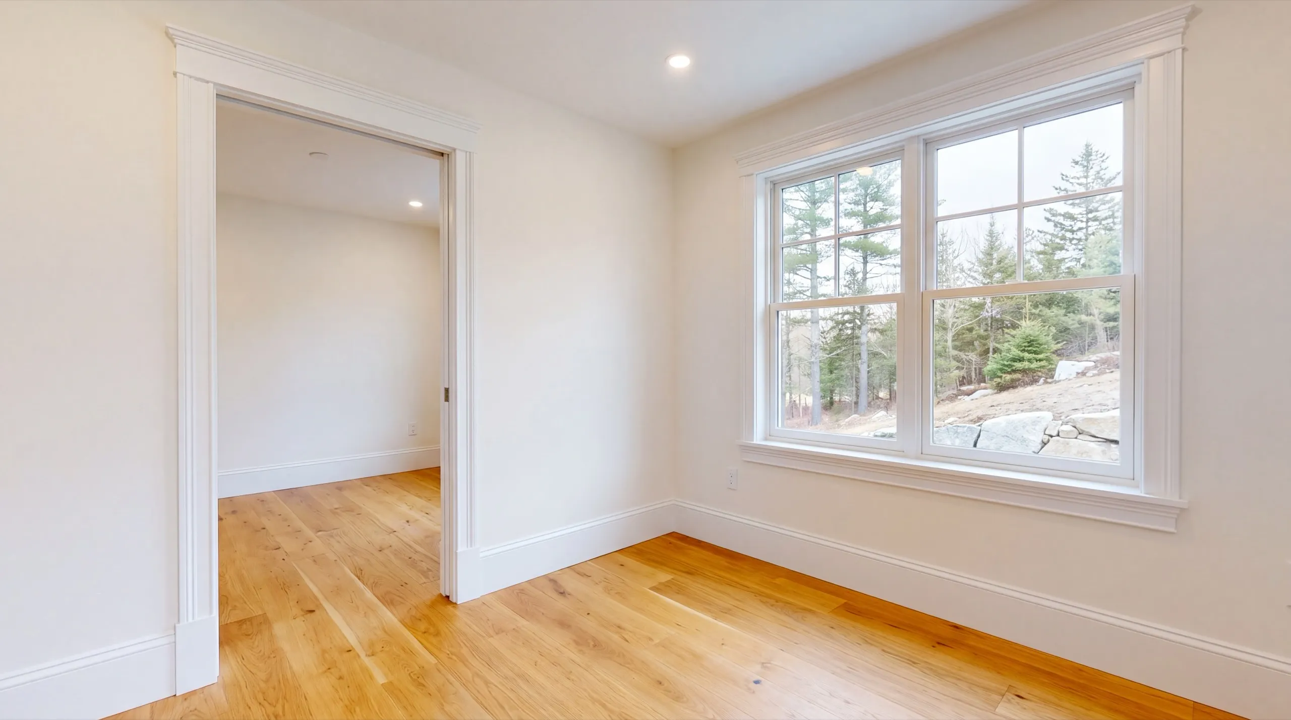 Home remodeling contractor Farmingdale Maine: finished white room with cased door and window trim and an oak floor