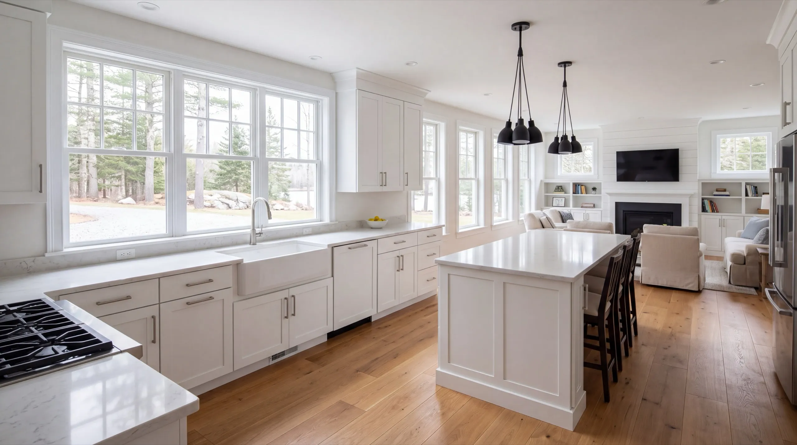 Remodeling in Richmond, ME: finished white kitchen with an island and stools open to a family room
