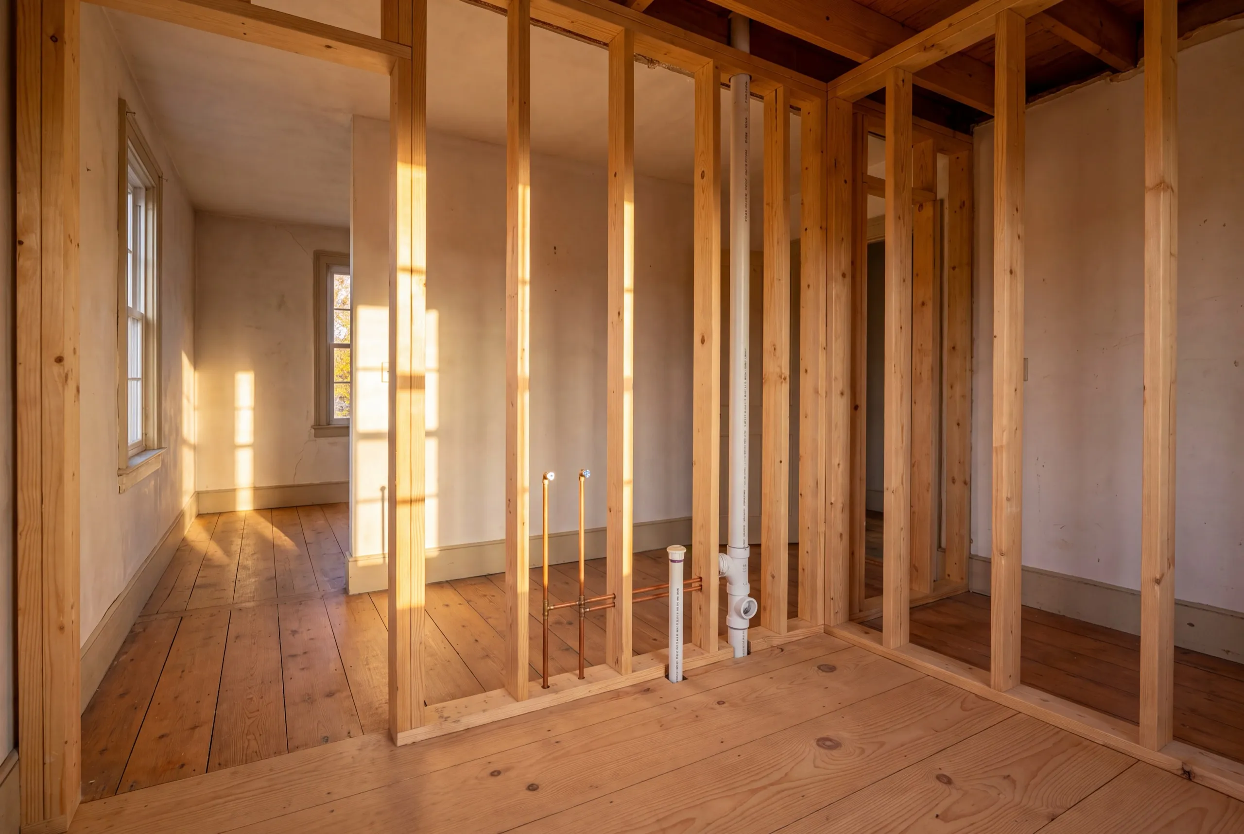 Remodeling Wiscasset Maine: new stud walls and plumbing stub-outs inside an older room with wide pine floors