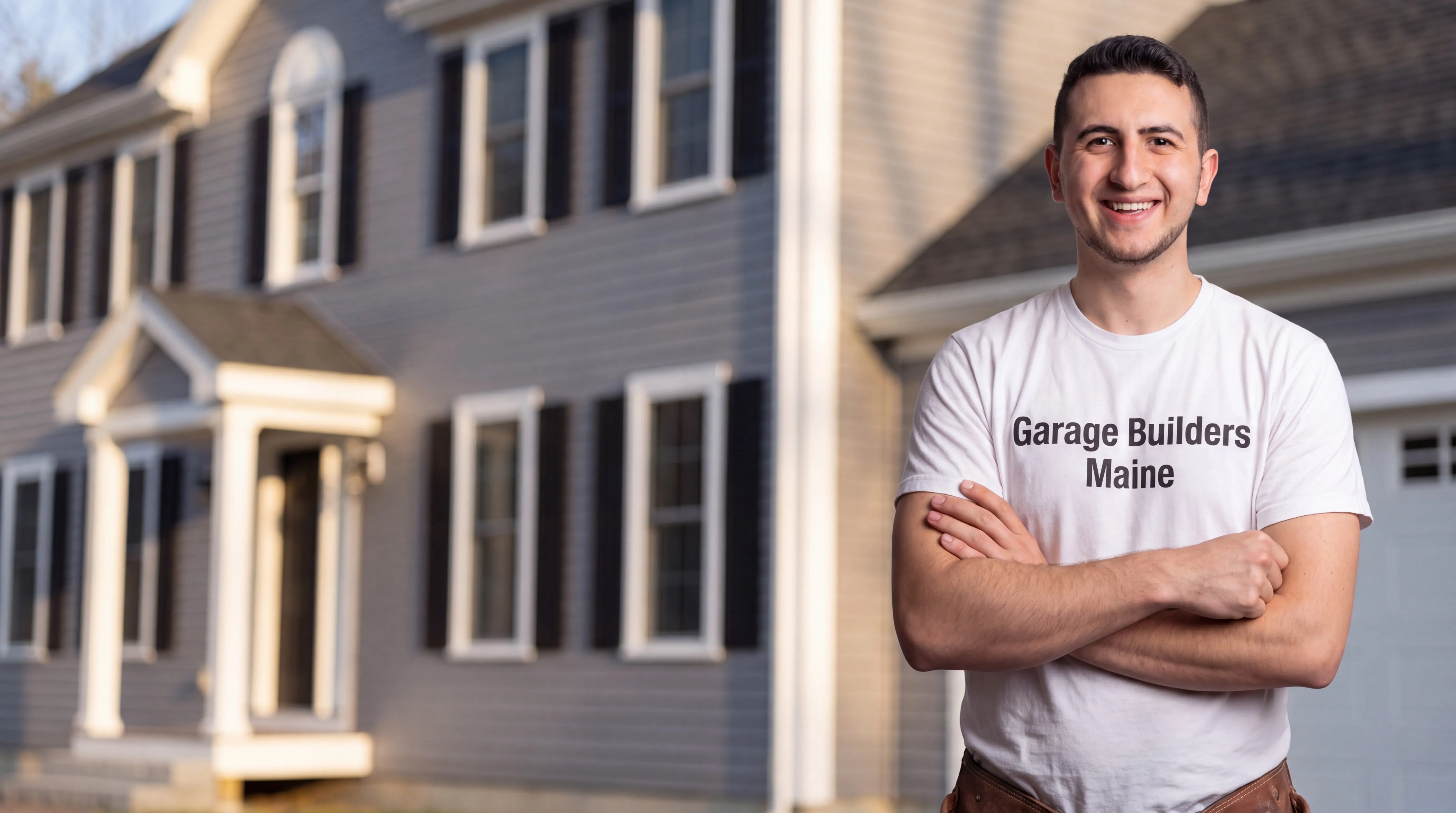 Owner of Garage Builders Maine standing with his arms crossed and smiling at a Maine job site